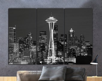 May include: A black and white photograph of the Seattle skyline at night, featuring the Space Needle and other skyscrapers.