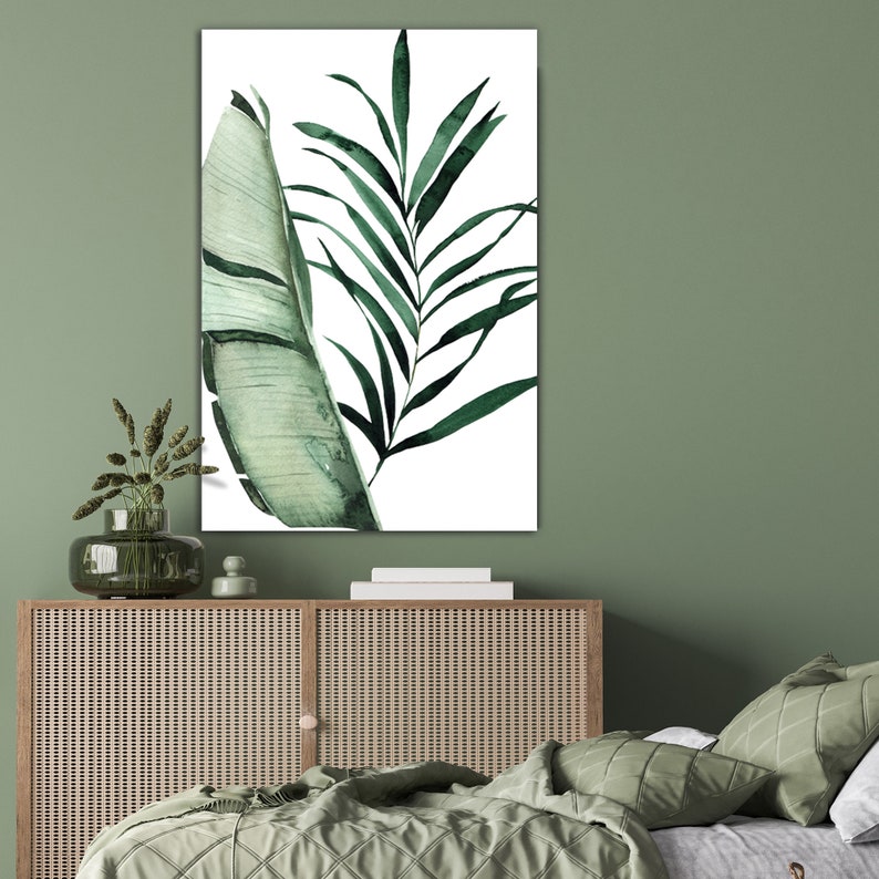 May include: A watercolor painting of green tropical leaves on a white background. The leaves are arranged in a vertical composition, with a large leaf on the left and a smaller leaf on the right.