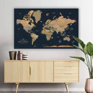 May include: A large world map with a dark blue background and gold-colored continents. The map includes the text "The Adventures Phil and Ronda". The map is displayed above a light wood cabinet with decorative items and a potted plant.