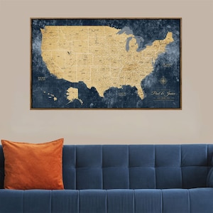 May include: A framed map of the United States with a vintage aesthetic. The map features a tan landmass against a dark blue background. The frame is a dark brown. The map is labeled with the names "Paul & Janice".