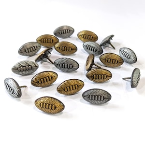 May include: A collection of metal football-shaped tacks in silver and gold tones. The tacks have a decorative design and are ideal for crafts and home decor.