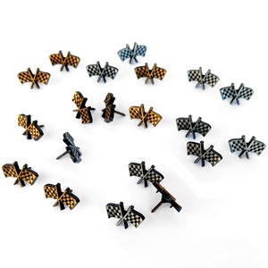 May include: A collection of 18 black and gold checkered flags, each with a pin on the back. The flags are arranged in a circular pattern on a white background.