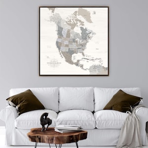 May include: A square wall art print featuring a map of North America with a light wood grain background. The map displays various shades of gray, beige, and brown. The text "SHAUN & JEAN" is printed in the lower left corner of the map.