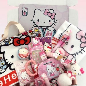 May include: A collection of Hello Kitty themed merchandise in a white box. Items include a tote bag, a cosmetic bag, a watch, a notebook, a pen, a hair tie, and various small figurines. The color scheme is primarily pink, white, and red.