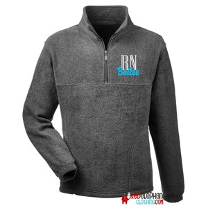 May include: A gray fleece pullover with a zippered neck. The shirt has a white embroidered "RN" and the name "Bailee" in blue lettering.