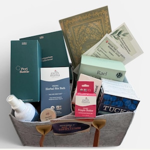 May include: A grey felt storage basket with brown leather handles containing various postpartum care products. Items include a Peri Bottle, Earth Mama Organic Herbal Sitz Bath, Earth Mama Organic Nipple Butter, Rael box, Tucks pads, and informational cards.