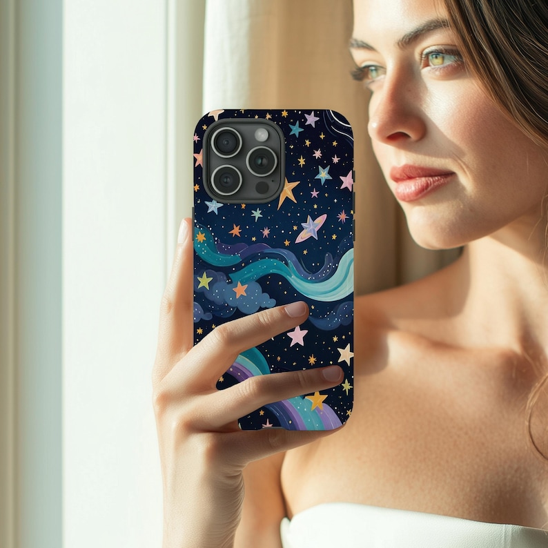 May include: A dark blue phone case featuring a whimsical design of stars, clouds, and a rainbow. The case has a glossy finish and a protective bumper around the camera lenses. The design includes various colors like yellow, pink, and blue.
