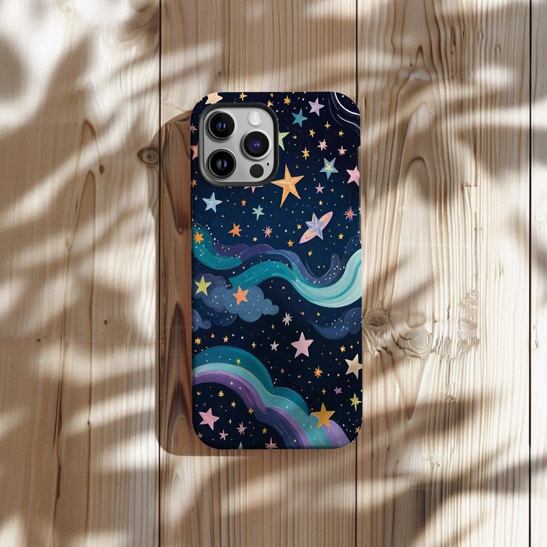 May include: A phone case with a dark blue background featuring a whimsical night sky design. The case is adorned with colorful stars, clouds, and a rainbow, creating a dreamy and artistic aesthetic. The case has a glossy finish.