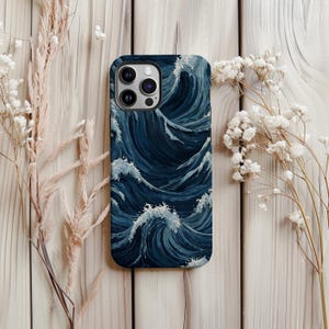 May include: A smartphone case with a dark blue ocean wave pattern. The case has a glossy finish and protective edges. The wave design features white crests and dark blue depths, creating a dynamic visual effect.