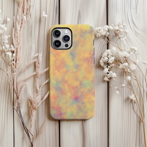 May include: A yellow phone case with a colorful, abstract design. The case features a pattern of blended colors, including yellow, orange, pink, and blue. The phone case is shown on a light wooden surface, with dried flowers.