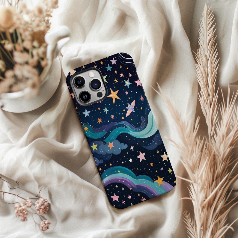 May include: A smartphone case with a colorful night sky design. The case features a dark blue background with illustrations of stars, clouds, and a rainbow. The stars are in various colors, including yellow, pink, and blue.