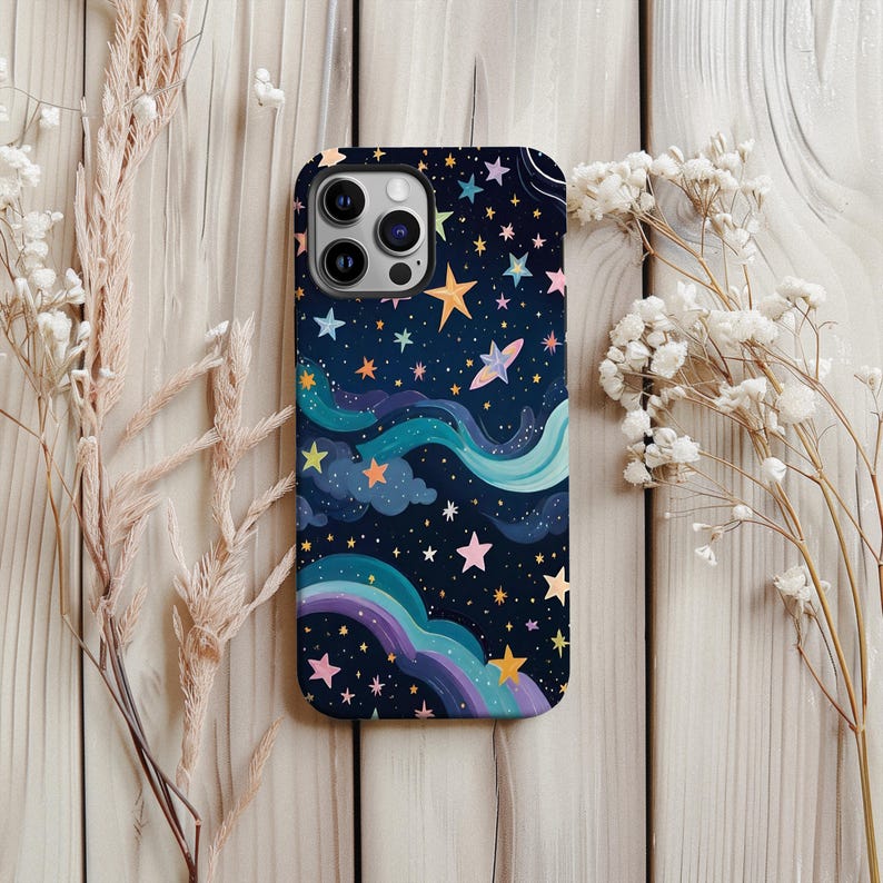 May include: A phone case with a whimsical night sky design. The case features a dark blue background with colorful stars, clouds, and a rainbow. The design is printed on a phone case with a camera cutout.