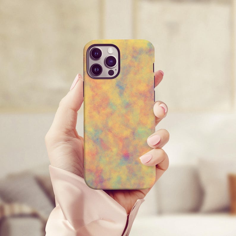 May include: A yellow phone case with a colorful, abstract design. The case has a smooth finish and a camera cutout. The design features a blend of orange, yellow, pink, and blue hues, creating a watercolor effect.