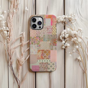 May include: A patterned phone case featuring a patchwork design with various floral and geometric patterns in shades of pink, orange, green, and beige. The case has a black border and a camera cutout.