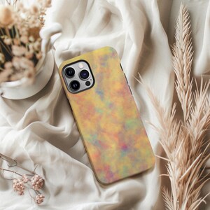 May include: A smartphone case with a colorful, abstract design. The case features a blend of yellow, orange, blue, and purple hues, creating a watercolor effect. The case has a black border and a camera cutout.