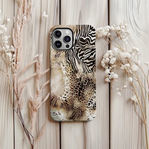 May include: A phone case with a mixed animal print design. The case features a combination of zebra stripes, leopard spots, and a marbled pattern in shades of brown, tan, and black. The case has a glossy finish and a camera cutout.