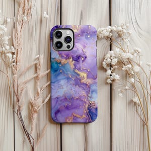 May include: A smartphone case with an abstract design in shades of purple, blue, and gold. The case has a marbled or watercolour effect. It is designed to fit a smartphone, with cutouts for the camera and buttons. The case is a decorative accessory.