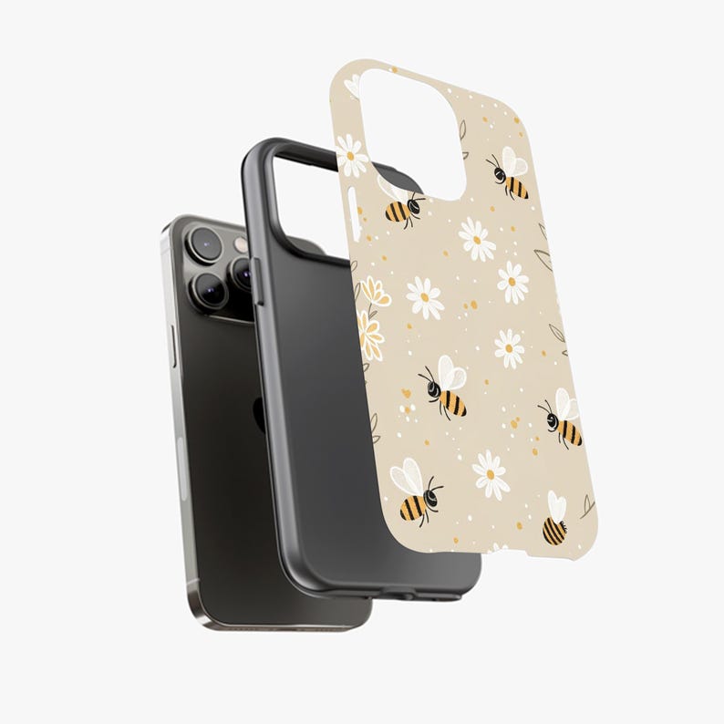 May include: A phone case with a beige background featuring a pattern of bees and white daisies. The case is shown in three parts: the phone, a black bumper, and the patterned cover. The bees have black and yellow stripes.