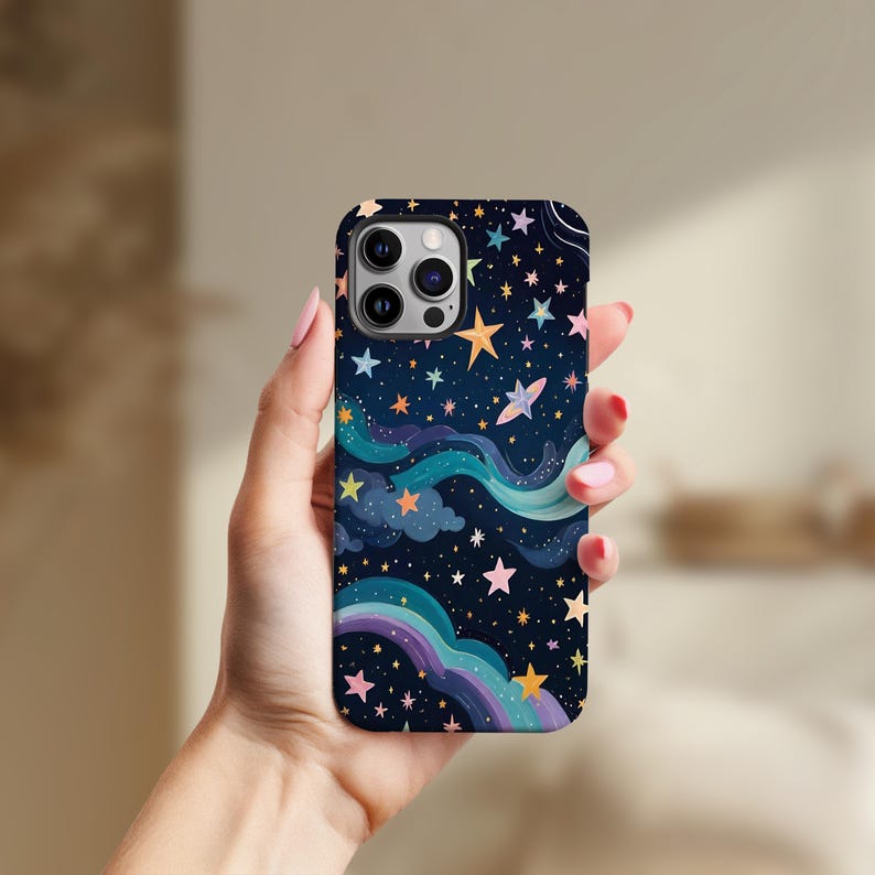 May include: A phone case featuring a whimsical night sky design. The case has a dark blue background with colorful stars, clouds, and a rainbow. The design includes yellow, orange, pink, and blue elements.