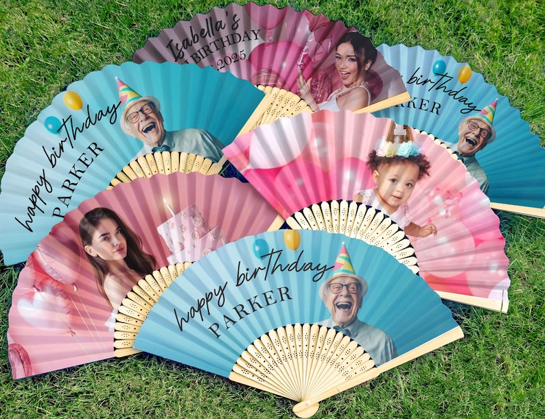 May include: A selection of personalised paper fans with bamboo handles, each displaying a photograph and birthday message. The fans feature images of people and the text "happy birthday" and names. The background colours are pink and blue.