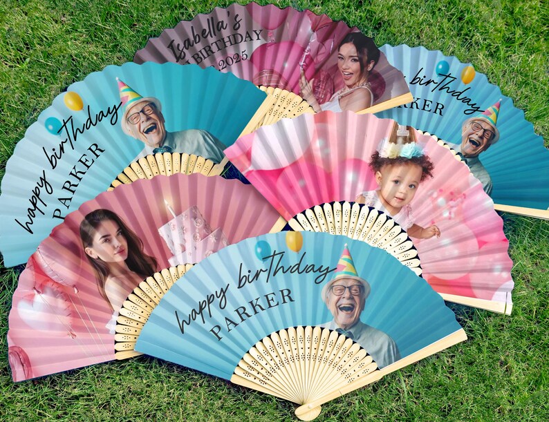 May include: A selection of personalised paper fans, each with a photograph and text. The fans display images of people and the words "happy birthday" and names. The fans are in pink and blue, with wooden handles.