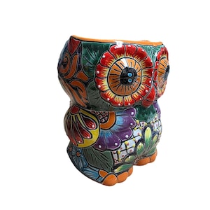 May include: A colorful ceramic owl figurine with a detailed floral design. The owl features vibrant red, orange, green, purple, and blue hues. The owl's eyes are black, and the feet are orange. The owl is a decorative item.