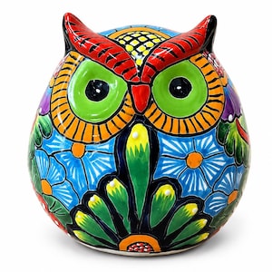 May include: A ceramic owl figurine featuring a vibrant hand-painted design with bright blue, green, orange, and red colors. The owl has large green eyes, orange circular patterns around the eyes, and a body covered in blue floral motifs.