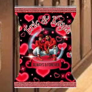 Puede incluir: Una bolsa negra con una parte superior roja brillante y un diseño con una pareja en una bola de nieve. La bolsa tiene corazones rojos y las palabras "Eric & Kayla" y "ALWAYS & FOREVER".
