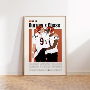 Peut inclure: Affiche encadrée représentant deux joueurs de football américain en uniforme des Bengals, s'embrassant. Le texte "Burrow x Chase" est en haut, avec les numéros de maillot visibles. Le fond est un mélange de blanc et d'orange.