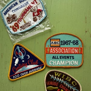 May include: Vintage bowling patches with embroidered text and graphics. One patch is in a plastic bag. The patches feature text such as "American Bowling Congress Tournament", "Century Club", and "League Champion".
