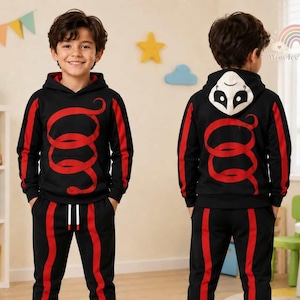 Puede incluir: Un conjunto de sudadera con capucha negra y pantalones deportivos a juego, con un gráfico de serpiente roja enroscada en la parte delantera y trasera. La capucha incluye un diseño de cara de panda en blanco y negro, con franjas rojas laterales.