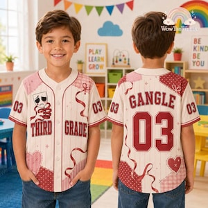 Pode incluir: Uma camisa de beisebol cor de creme com riscas vermelhas finas, apresentando o texto 'THIRD GRADE' e um gráfico de máscara de teatro triste na frente. As costas exibem o nome 'GANGLE' e o número '03' em letras vermelhas com corações.