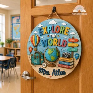 May include: A round wooden wall sign featuring the text EXPLORE THE WORLD and Mrs. Atlas. The design includes a colorful hot air balloon, a teal suitcase, a globe, a camera, stacked books labeled Adventures, Cultures, Discoveries, and directional signs.