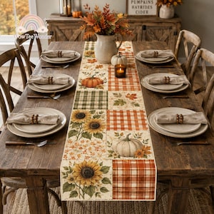 May include: A rectangular table runner featuring a patchwork design of orange and white plaid, green plaid, sunflowers, pumpkins, and autumn leaves. The runner is centered on a wooden dining table set with white plates and beige napkins.