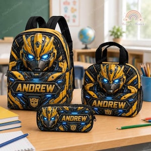 May include: A yellow and black backpack, lunch bag, and pencil case set featuring a robotic character face with glowing blue eyes and the name ANDREW printed in bold letters on each item, along with a small Autobot logo emblem on the front.