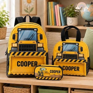 May include: A yellow backpack, a matching lunch bag, and a pencil case, all featuring a construction vehicle design with black hazard stripes and the name COOPER printed in bold black letters on each item. The items have black straps and accents.