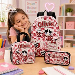May include: A backpack, lunch bag, and pencil case set featuring a red and white checkered pattern with theater mask graphics, red ribbons, and the name Olivia printed in red. Each item displays the text Gangle and various mask illustrations.