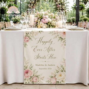 May include: A white table runner featuring a floral border of pink and white roses with green leaves. The text reads: Happily Ever After Starts Here, Madeline & Andrew, September 2026. The runner is displayed on a table with glassware and flowers.