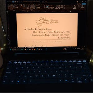 May include: A laptop screen shows text: "A Guided Reflection for... Out of Sync, Out of Spark: A Gentle Invitation to Step Through the Fog of Languishing." Two glass cylinders with lit candles and a beige container are also visible.