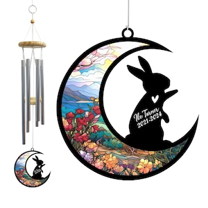 May include: Decorative wind chimes with a wooden top and silver tubes. A black silhouette of a rabbit inside a crescent moon with a colorful floral and landscape design. The text "Ike Turner 2021-2024" is visible.