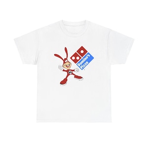 May include: White t-shirt featuring a cartoon character in a red suit with long ears, a red and white Domino's Pizza logo, and the words "Domino's Pizza" in blue. The character is in a dynamic pose.