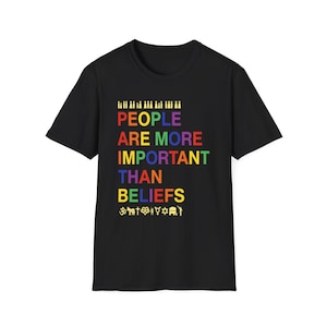 May include: Black t-shirt with the text "PEOPLE ARE MORE IMPORTANT THAN BELIEFS" in rainbow colors. The shirt also features small icons representing various religions and beliefs.