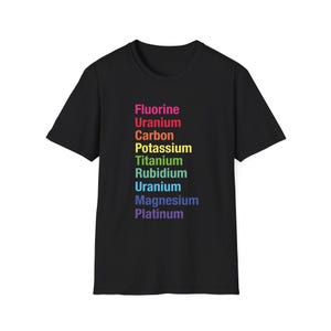 Puede incluir: Una camiseta negra de manga corta con una lista vertical de elementos químicos impresos en colores arcoíris. El texto dice Fluorine, Uranium, Carbon, Potassium, Titanium, Rubidium, Uranium, Magnesium y Platinum en una columna.