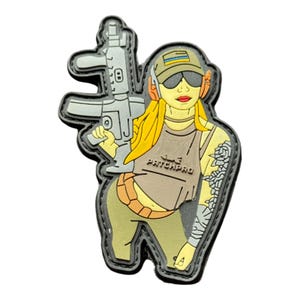 May include: A PVC patch depicting a cartoon figure holding a rifle. The figure wears a cap, sunglasses, and a tank top with "PATCHPRO" text. The patch, with a black border, uses tan, grey, and yellow hues.