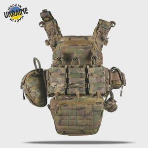 Op de afbeelding: Een camouflage tactisch vest met meerdere zakken en bevestigingspunten. Het vest is ontworpen voor militair of buitengebruik, met verstelbare bandjes en een modulair ontwerp. De tekst "MADE IN UKRAINE" is zichtbaar.