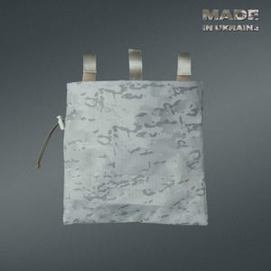 May include: A white and gray camouflage pouch with three tan straps at the top and a drawstring closure. The text "MADE IN UKRAINE" is visible in the upper right corner. The pouch is designed for carrying small items.
