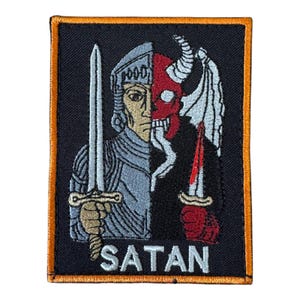 May include: A rectangular embroidered patch with an orange border on a black background. The design features a split figure: a knight in silver armour holding a sword on the left, and a red horned demon with a wing on the right. The word SATAN is below.
