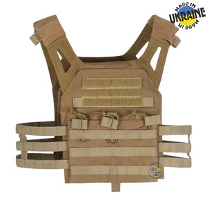 May include: A tan tactical plate carrier vest featuring MOLLE webbing, adjustable shoulder straps, and a front panel with hook-and-loop sections. The vest includes a skeletonized cummerbund system and a circular logo in the corner with the text Made in Ukraine.