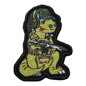 May include: Embroidered patch featuring a cartoon dinosaur in military gear, including a helmet, headset, and tactical vest. The dinosaur is holding a rifle and has a red tongue sticking out. The patch has a black border.