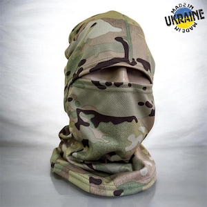 May include: A camouflage balaclava made of a textured, breathable mesh fabric featuring a multi-colored pattern of tan, brown, and green. The headgear includes a single large eye opening and a circular stamp in the corner that reads MADE IN UKRAINE.